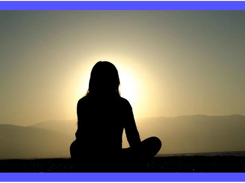 Persona in meditazione profonda con le mani giunte, circondata da luce tranquilla e serena.