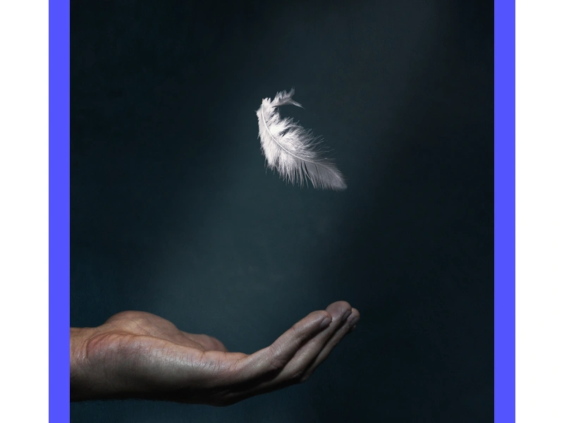 L'immagine rappresenta una mano aperta con una piuma in equilibrio, simboleggiando la leggerezza e la flessibilità dell'orgoglio nella pratica spirituale.
