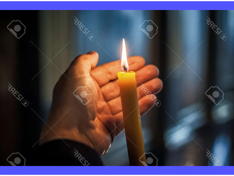 Immagine di una candela accesa e un crocifisso in primo piano, creando un'atmosfera di riflessione e spiritualità per le preghiere di Settimana Santa.